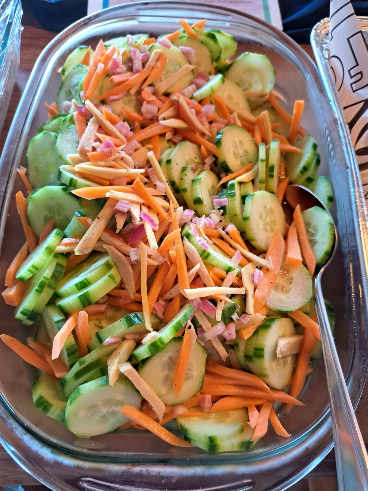 Fresh cucumber salad with sliced cucumber, carrots and red onion in a serving dish