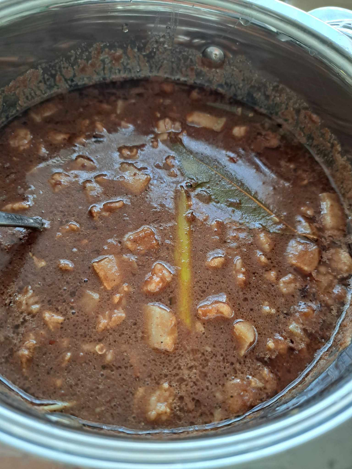 Homemade dinuguan simmering in a cooking pot with bay leaves