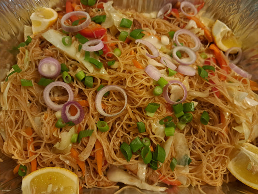 Pancit bihon with cabbage, carrots, spring onions and lemon in a foil tray