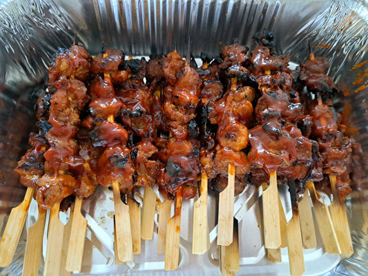 Cooked Filipino chicken barbecue skewers in a serving tray