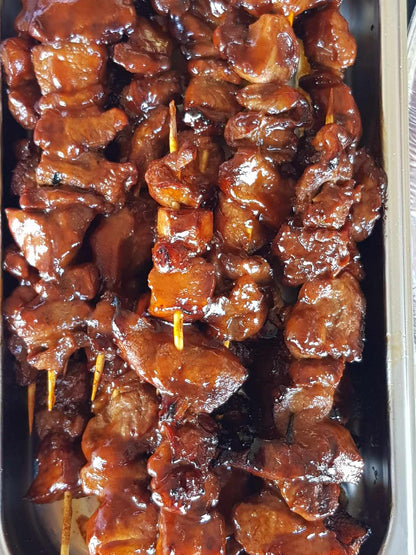 Top view of glazed Filipino pork barbecue skewers in a tray