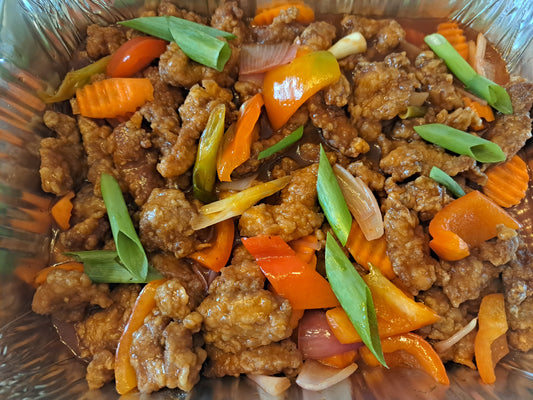 Sweet and sour pork with colourful vegetables in a large catering tray