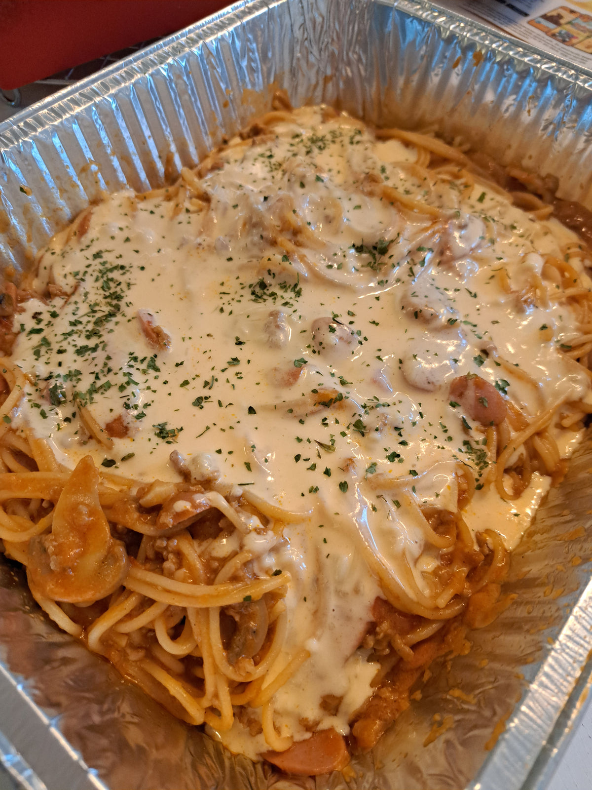 Angled view of sweet-style spaghetti covered with creamy melted cheese