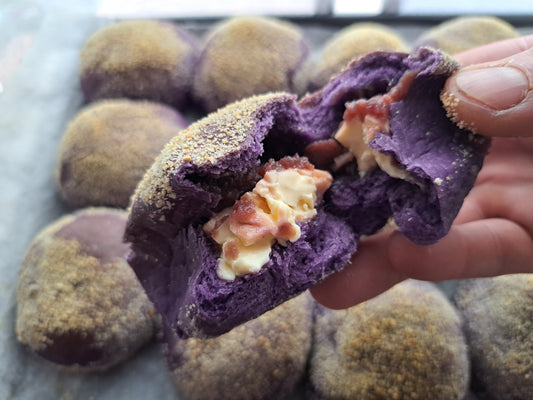 Ube cheese pandesal pulled open to show melted cheese and purple crumb