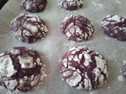 Freshly baked ube crinkle cookies cooling on baking paper
