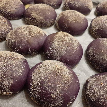 Close-up of freshly baked ube pandesal dusted with fine breadcrumbs