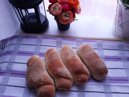 Four sugar-dusted Spanish bread rolls arranged on a checked cloth