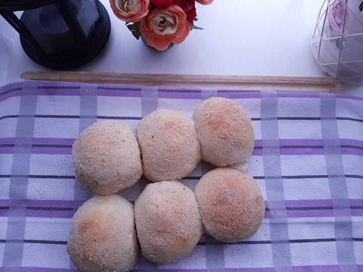 Six classic pandesal rolls arranged on a checked cloth