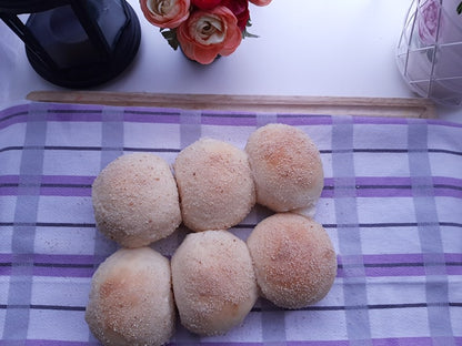 Six classic pandesal rolls arranged on a checked cloth