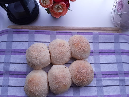Six classic pandesal rolls arranged on a checked cloth