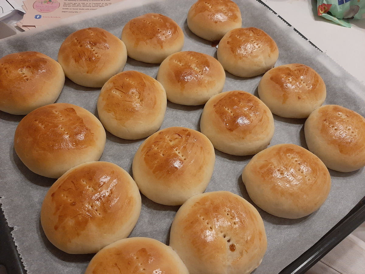 Tray of freshly baked pan de coco with golden egg-washed tops