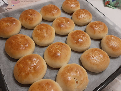 Tray of freshly baked pan de coco with golden egg-washed tops