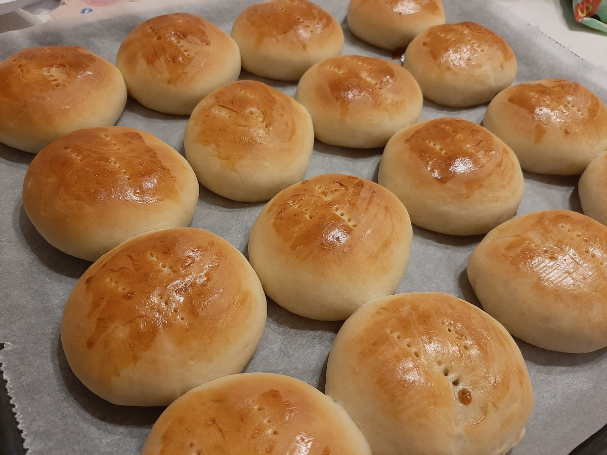 Close-up of round pan de coco rolls cooling on baking paper