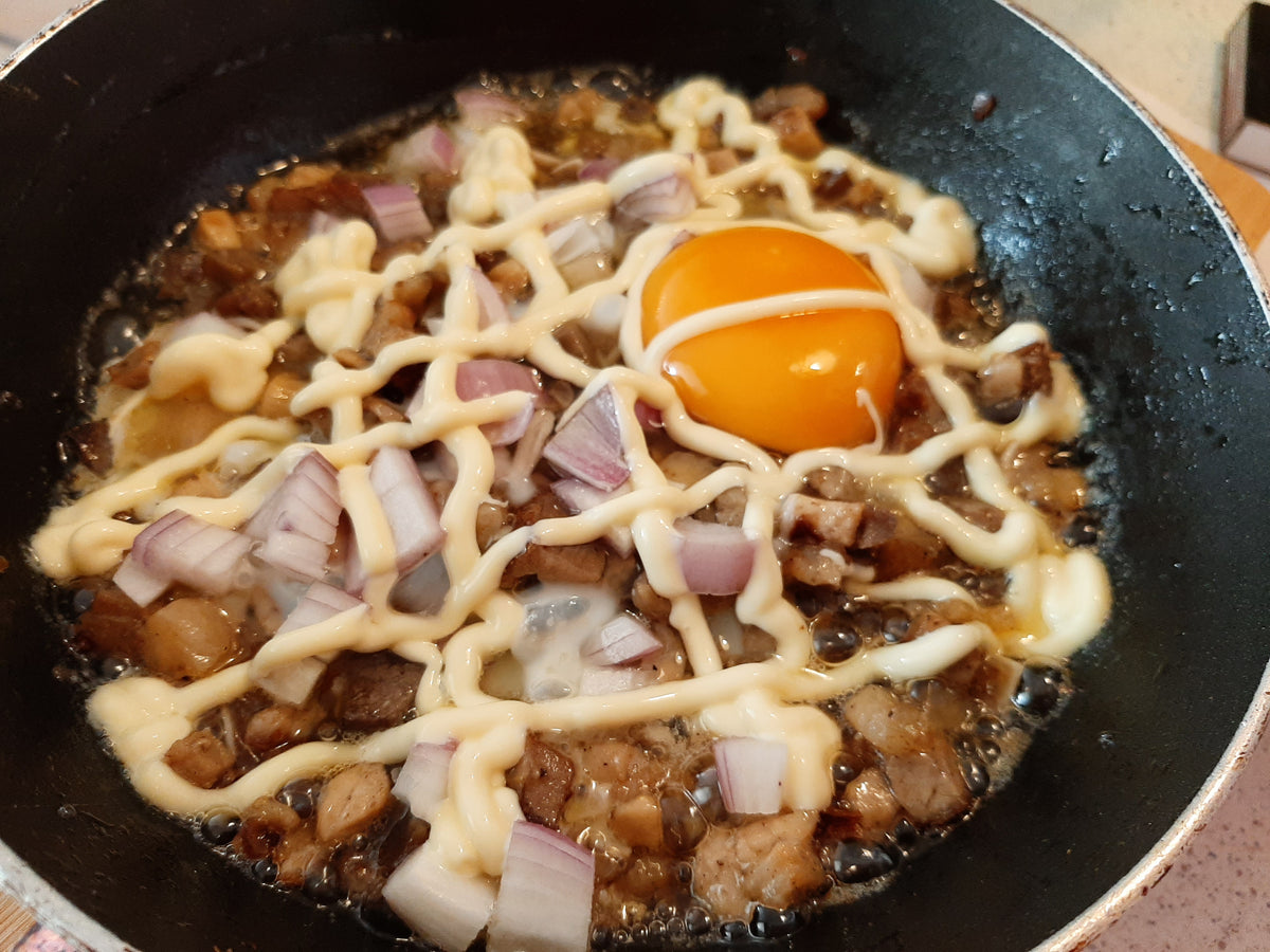 Sizzling pork sisig with mayonnaise, chopped onions and a raw egg yolk