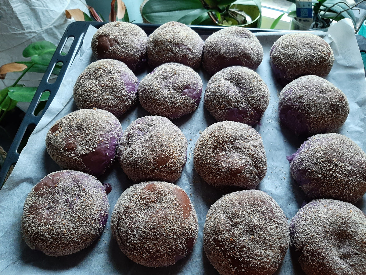 Freshly baked ube cheese pandesal arranged on a lined tray
