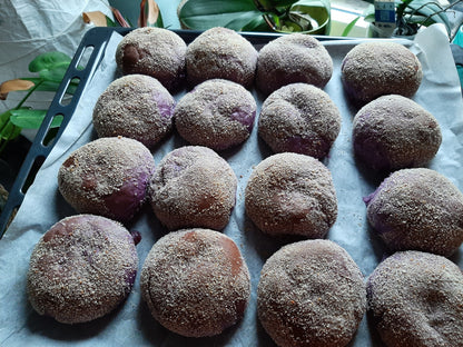 Freshly baked ube cheese pandesal arranged on a lined tray