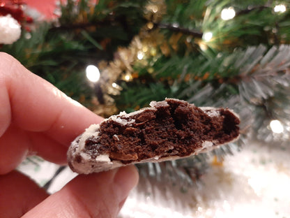 Hand holding a bitten choco crinkle in front of a Christmas tree