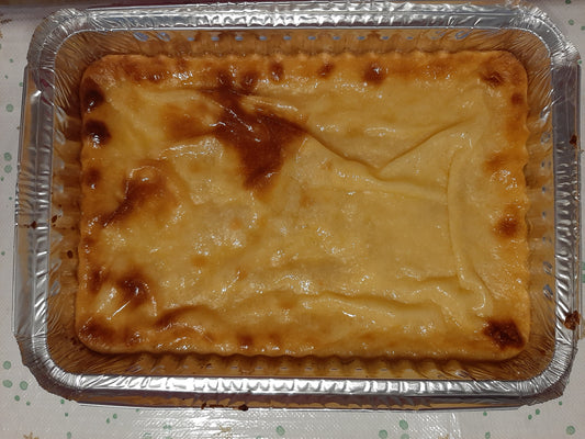 Homemade Filipino cassava cake with a glossy golden top in a large foil tray