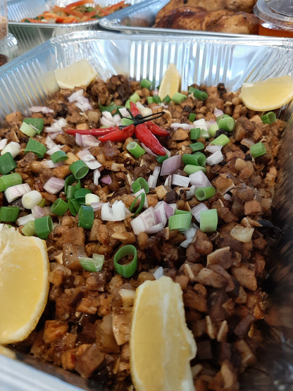 Catering tray of pork sisig with onions, chillies and lemon wedges