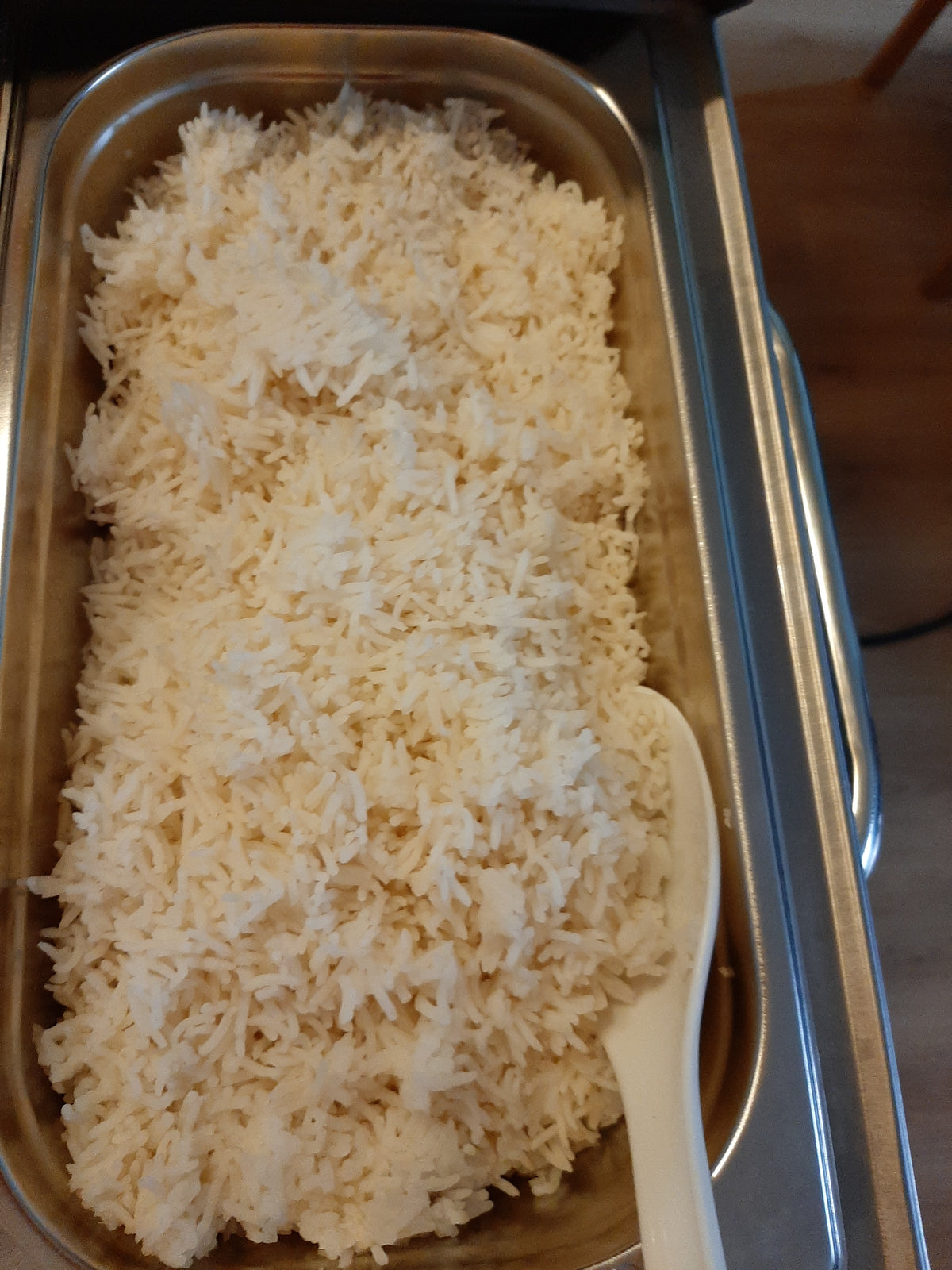 Deep buffet pan of fluffy plain white rice with a serving spoon