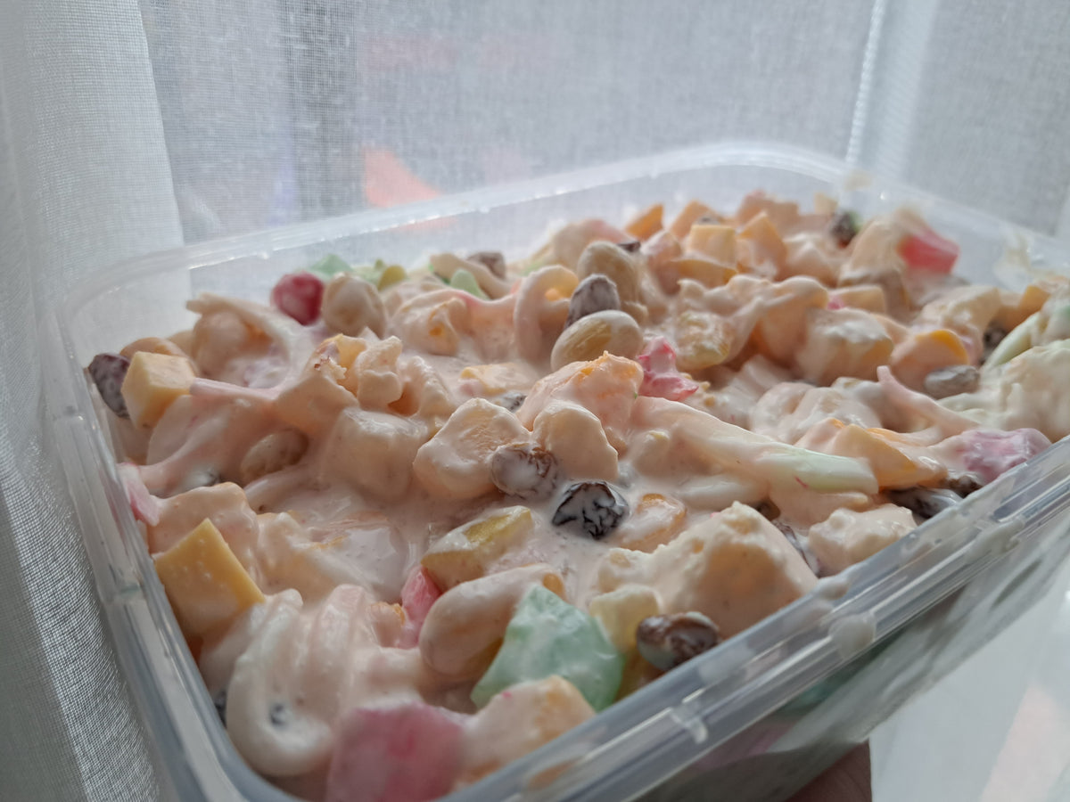 Open tub of Filipino fruit salad with colourful fruit and raisins