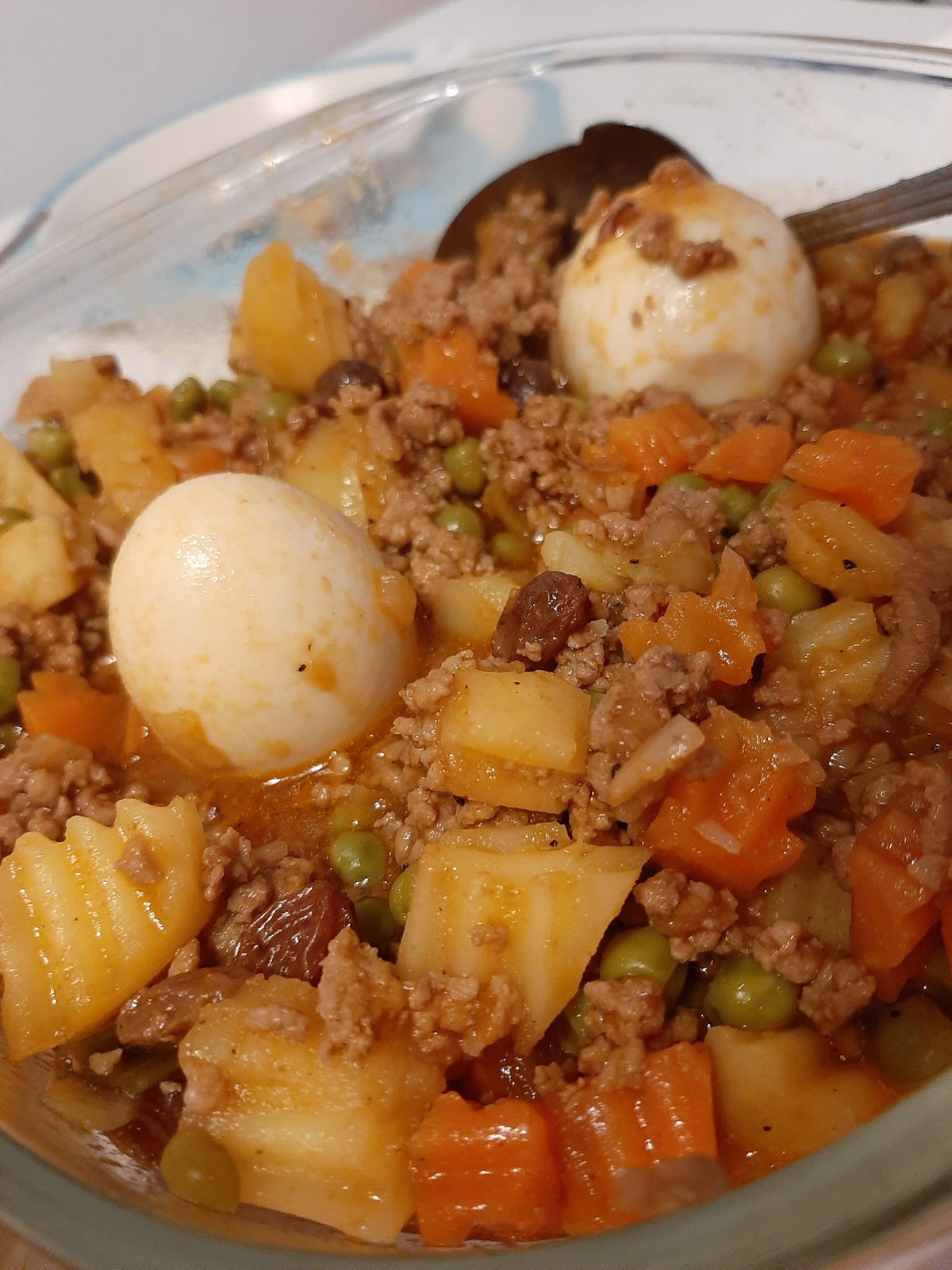 Pork giniling with colourful vegetables and boiled eggs served in a glass dish