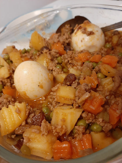 Pork giniling with colourful vegetables and boiled eggs served in a glass dish