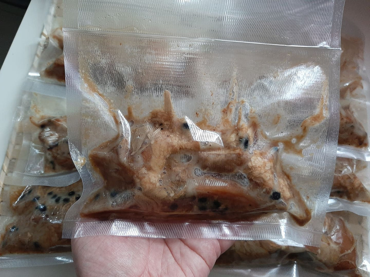 Hand holding a sealed 200 g pork humba portion