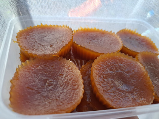 Close-up of glossy amber Filipino kutsinta in a clear food container