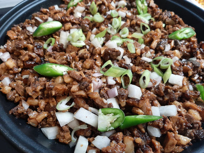 Close-up of pork sisig with chopped onions and sliced green chillies