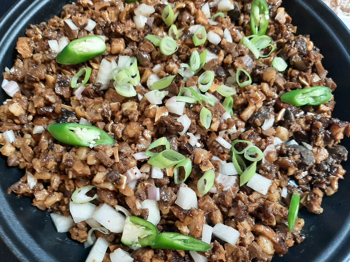 Detailed overhead view of crisp pork sisig with fresh onion garnish