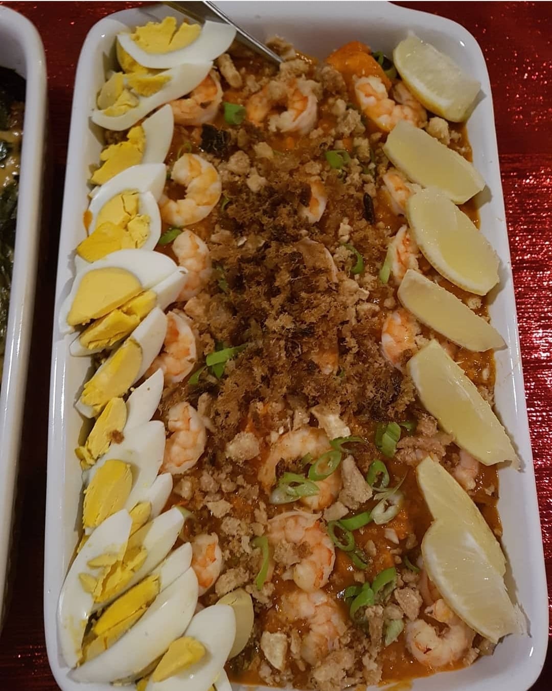 Long tray of pancit palabok bordered with egg slices and lemon wedges