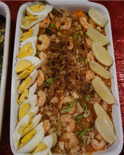 Long tray of pancit palabok bordered with egg slices and lemon wedges