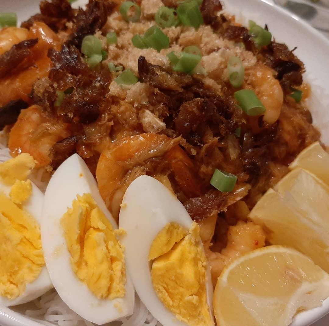 Close-up of pancit palabok with shrimp, egg wedges and spring onions
