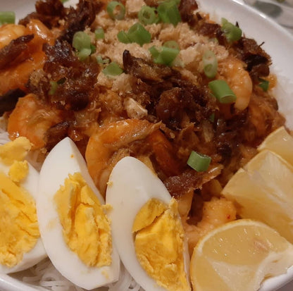 Close-up of pancit palabok with shrimp, egg wedges and spring onions