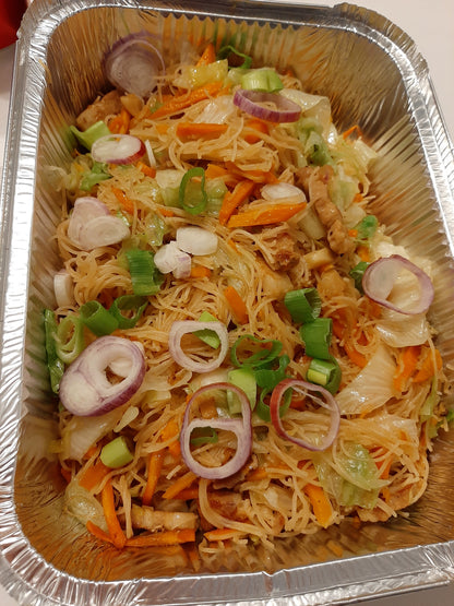 Full catering tray of pancit bihon garnished with onion rings and spring onions