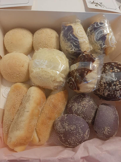 Assorted Filipino bread box with pale rolls, ube buns and wrapped pastries