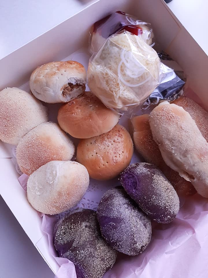 Overhead view of a mixed Filipino bread box with pandesal and ube rolls