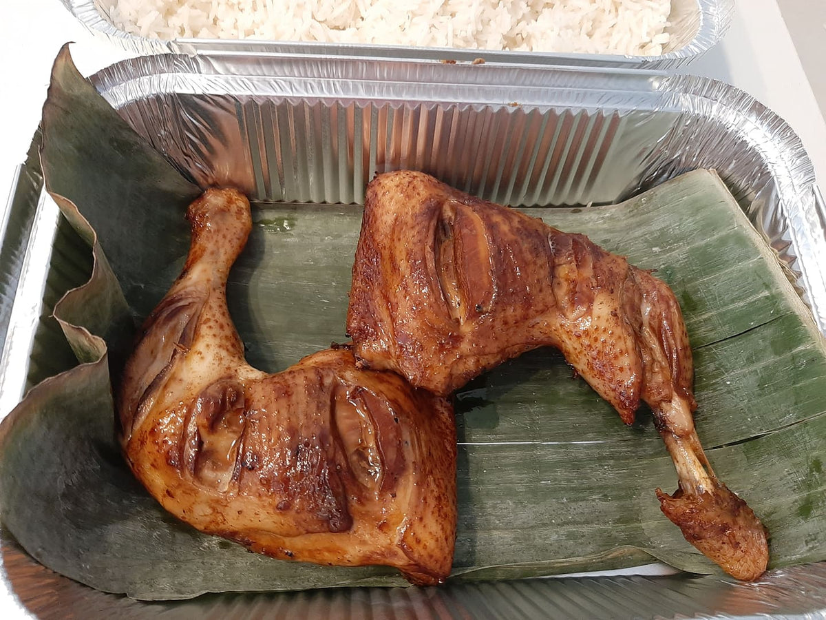 Three baked chicken inasal leg quarters arranged on banana leaves
