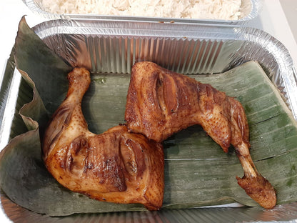 Three baked chicken inasal leg quarters arranged on banana leaves