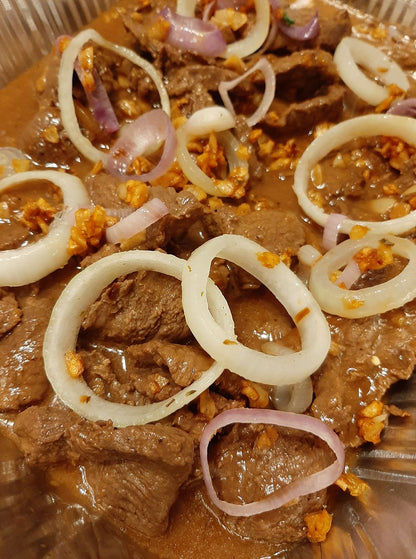 Detailed view of Bistek Tagalog beef slices in onion sauce