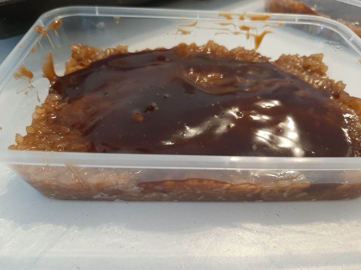Side view of biko bibingka malagkit and caramel topping in a takeaway tub