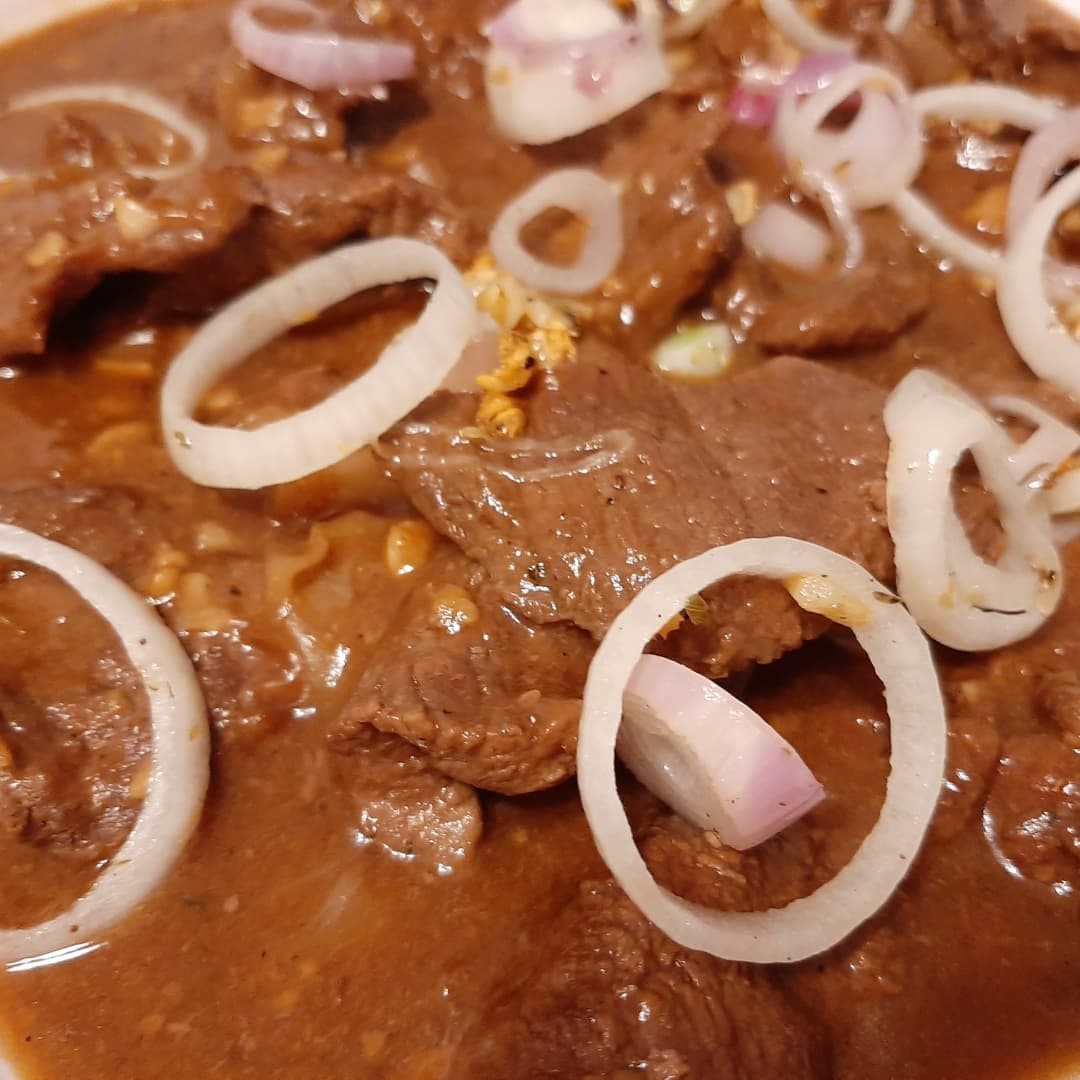 Close-up of saucy Filipino beef steak with sliced red onions