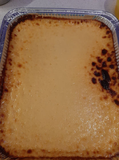 Close-up of creamy cassava cake with browned edges in a foil baking tray