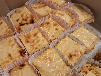 Individual Filipino cassava cake squares arranged in a takeaway box