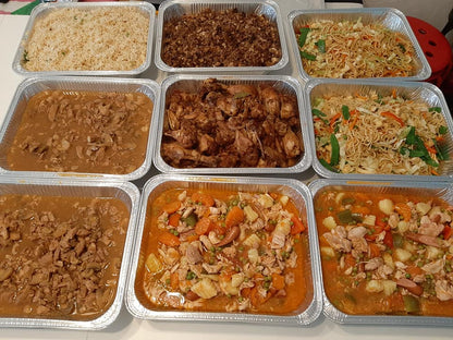 Catering spread featuring chicken adobo with rice, noodles and other dishes