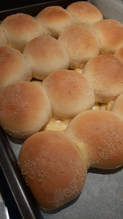 Rows of round cheese pandesal with evenly browned breadcrumb tops