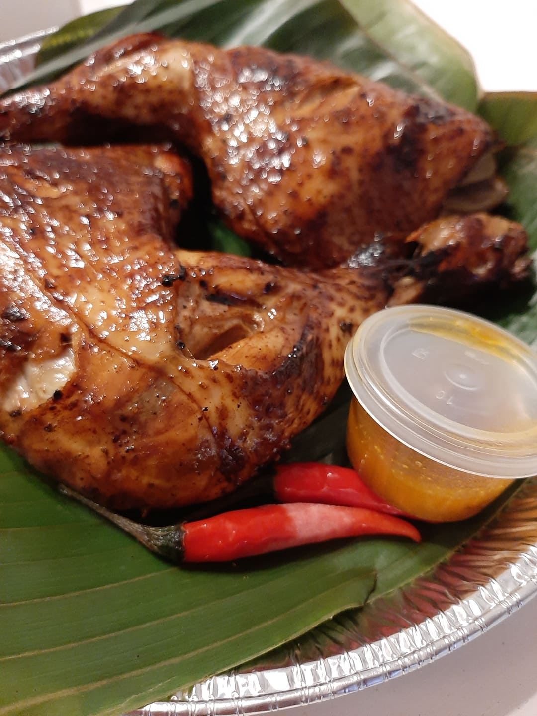 Close-up of glazed baked thigh inasal with red chillies and dipping sauce