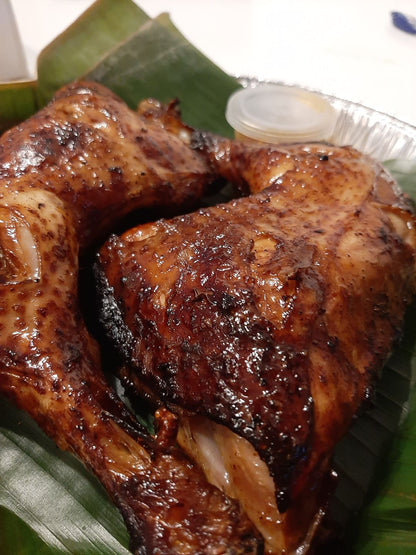 Baked chicken inasal thigh with browned skin on a banana leaf