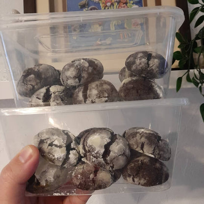 Two clear boxes filled with powdered-sugar chocolate crinkles